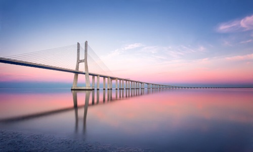 bridge over water with pink and blue sky 
